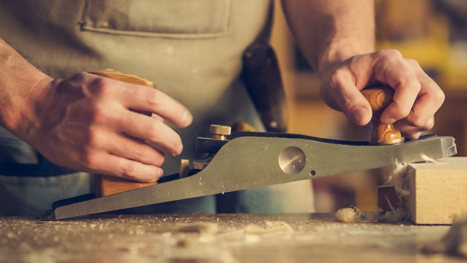 Carpintero trabajando la madera con un cepillo manual