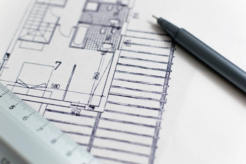 Planos de arquitectura sobre una mesa, con una regla y un lápiz